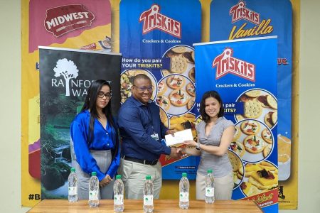 Banks DIH Water Beverages Manager,  Colin King, hands over the sponsorship cheque to  Mary Fung-A-Fat in the presence of Biscuit Manager, Shenisa Fredericks.
