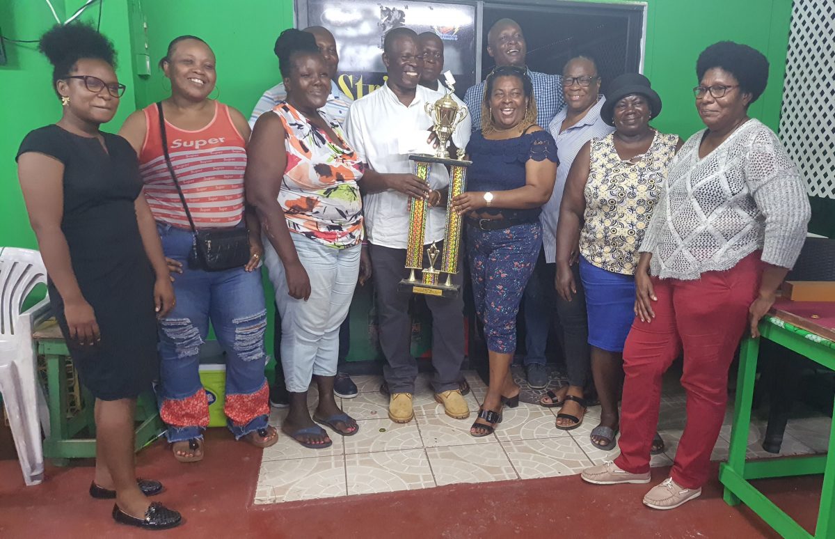 Morse Archer, Managing Director of Cevons Waste Management donates the first prize with the trophy to the Vice President of the World Council of Domino Federation Veda Debelotte in the presence of the team captains and other sponsors for the “Salute to Mothers” domino tourney