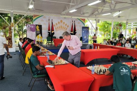 Grandmaster Nigel Short makes his move with the white pieces against Ricardo Narine on Board Seven during yesterday’s simultaneous exhibition at State House. (Donald Duff photo)