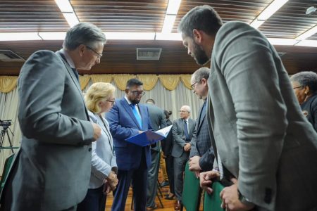 President Irfaan Ali (centre) perusing the elections report in the presence of diplomats yesterday at the Office of the President. (Office of the President photo) 