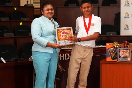 Education Minister Priya Manickchand making a presentation to the top Whiz Kid, Joseph Prendergast (Ministry of Education photo)