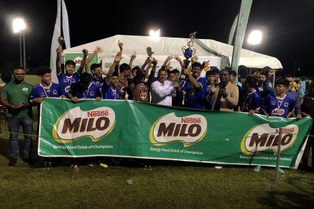 Ministry of Housing Colin Croal presents the championship trophy to Santa Rosa captain Roy Van Sluytman in the presence of his teammates after they won the Milo Secondary School Football Championships last night in their debut season