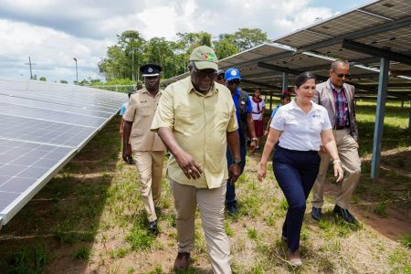 Prime Minister Mark Phillips (left) touring the solar farm. At right is by IDB Country Representative, Lorena Salazar.