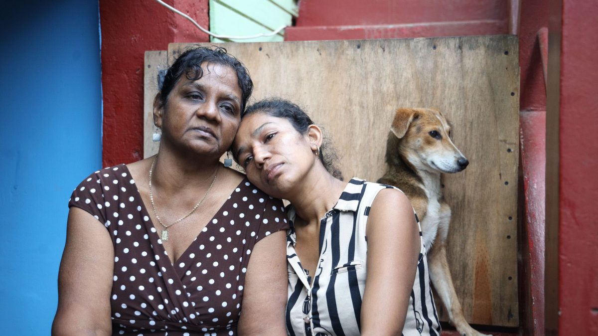 A grieving Linda Bajnath, left, comforts her daughter- in-law Parbatee Kumar at their Penal home yesterday, one day after her son Anand Kumar, grandson Kishore and son-in-law Rolly Hosein were killed.
