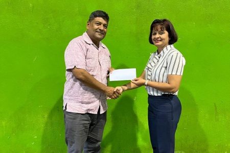 Assistant Secretary of the Guyana Olympic Association Emelia Ramdhani hands over sponsorship cheque to Robert Singh, Treasurer and Director of Archery Guyana.