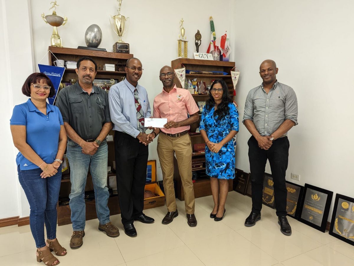  President of the Guyana Olympic Association Godfrey Munroe, Secretary-General, Vidushi Persaud-McKinnon, Treasurer, Garfield Wiltshire who is handing over sponsorship cheque to Ryan Sampson, Honorary Secretary of the Guyana NRA, Dylan Fields, Full-Bore Captain of the Guyana NRA and Emelia Ramdhani, Assistant Secretary of the Guyana Olympic Association. 
