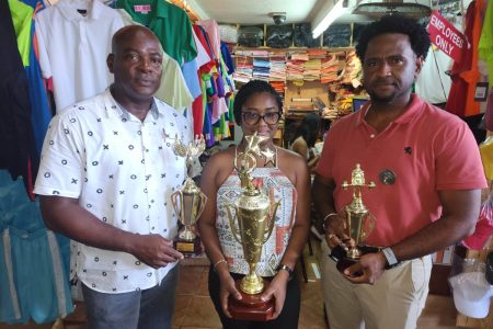 Tanya Crossman of the Trophy Stall, flanked by GAPLF’s Franklin Wilson (left) and Denroy Livan, displays some of the trophies. 
