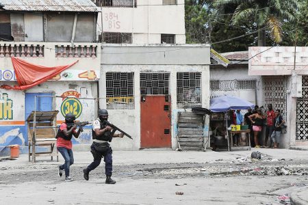 People huddle in a corner as police patrol the streets after gang members tried to attack a police station in Port-au-Prince, Haiti, April 25, 2023. (Reuters photo)