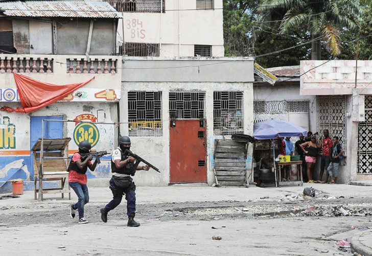 People huddle in a corner as police patrol the streets after gang members tried to attack a police station in Port-au-Prince, Haiti, April 25, 2023. (Reuters photo)