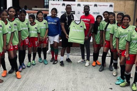 ExxonMobil Community Relations Advisor Ryan Hoppie handing over the team uniforms to the Bartica Secondary U14 girls team.
