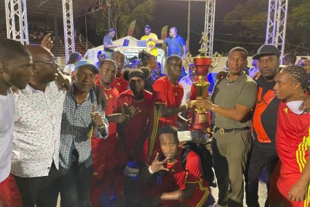 Adrian Aaron of Bent Street receives the championship
trophy from Co-Director of the Kashif and Shanghai Organization and Chairman of the National Sports Commission Kashif Muhammad, in the presence of teammates and tournament officials after winning the ‘One Guyana’ Futsal Championship