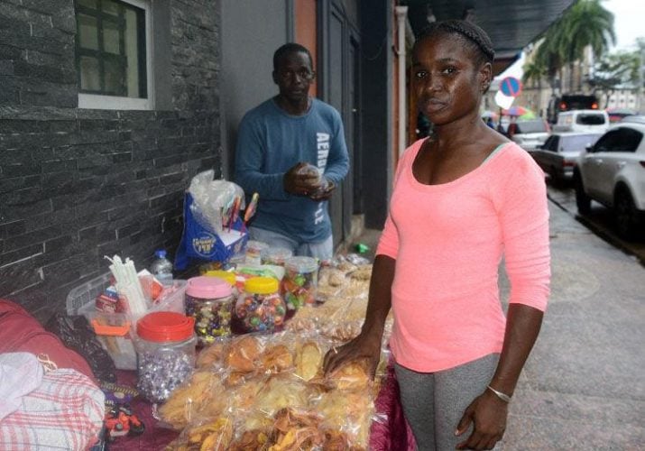 Guyanese nationals Candy Oudkerk and her husband, Paul Benjamin, arrange homemade treats for sale on Independence Square, Port of Spain, yesterday. The couple empathised with the parents of 19 children who perished in the dorm fire in Guyana. —Photo: Ishmael Salandy