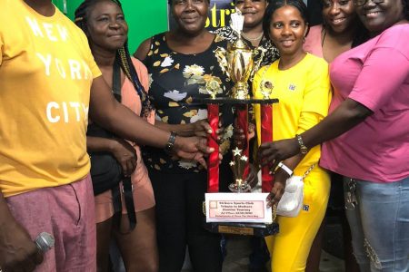 Tournament coordinator Roderick Harry (left) presents the first place package to the victorious C-Point unit who were crowned  champions of the ‘Tribute to Mothers’ Domino Championship