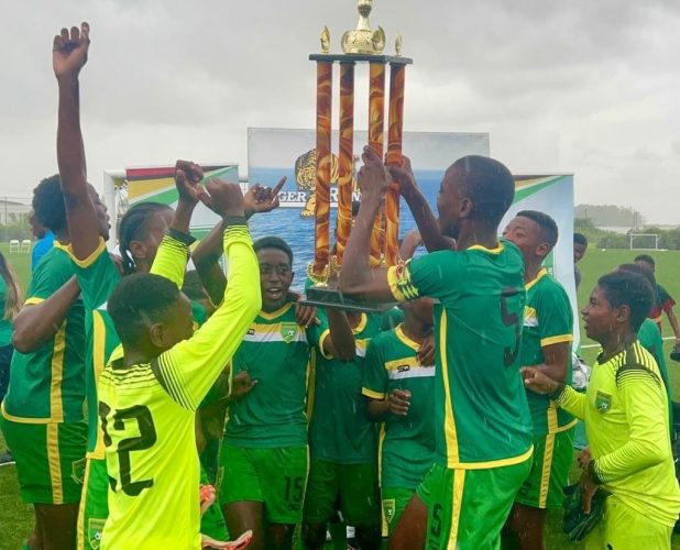 East Coast Demerara celebrates their Tiger Rentals League Cup triumph in the rain following their final’s win over Bartica at the National Training Centre, Providence yesterday.