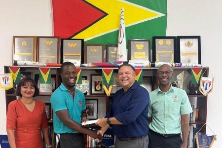 Willon Cameron receiving a cheque from Vice-President Philip Fernandes. At left is Assistant Secretary of the Guyana Olympic Association, Emelia Ramdhani and at right is Garfield Wiltshire, Treasurer of GOA.