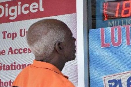 A Lotto player looks at the signage at a National Lotteries Control Board outlet on Pointe-a-Pierre Road, San Fernando, on Wednesday, advertising the Lotto Plus jackpot of $18.5 million.