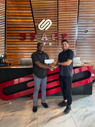 Manager of Space Gym 2.0, Lucas Matos (right) presents the sponsorship cheque to GAPLF President, Franklin Wilson.