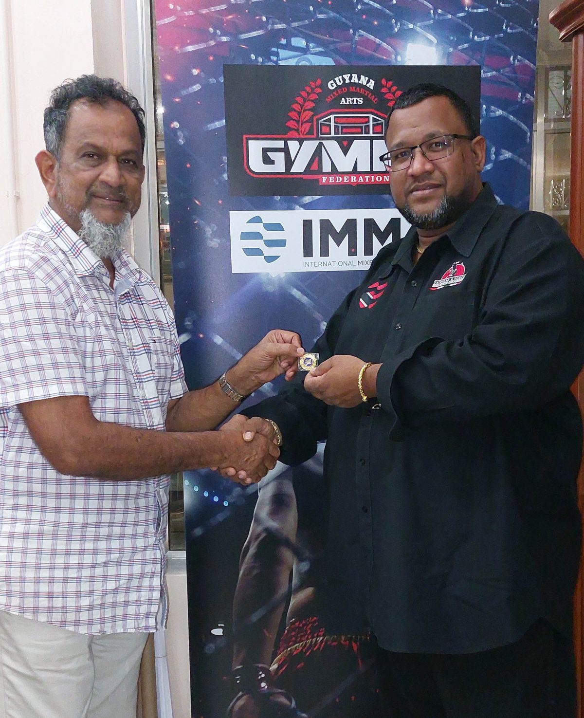 Mohamed’s Enterprise proprietor Nazir ‘Shell’ Mohamed (left) receiving the 10th-anniversary IMMAF gold pin from Jason Fraser, President of the Pan American Mixed Martial Arts Federation for this outstanding work in support of the sporting fraternity