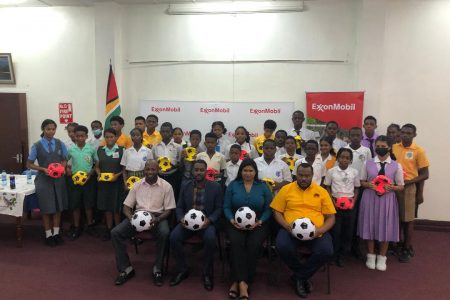 Troy Mendonca (sitting 1st from right), Co-Director of the Petra Organization, Gomatie Gangadin (2nd from right), Public Relations Manager of Guyana Shore Base, Ryan Hoppie (3rd from right), ExxonMobil Community Relations Advisor, and Kurt Brathwaite of the Allied Arts Department of the Ministry of Education pose with representatives of the competing schools following the end of the ball distribution exercise yesterday.