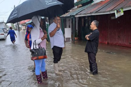 Regional Vice Chairman, Zamal Hussain (centre) checking the flood situation in Pitt Street, New Amsterdam yesterday. 