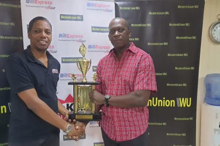 Chief Accountant of Grace Kennedy Money Services, Jermaine Samaroo, (left)
hands over the second place trophy to tournament coordinator Roderick Harry.