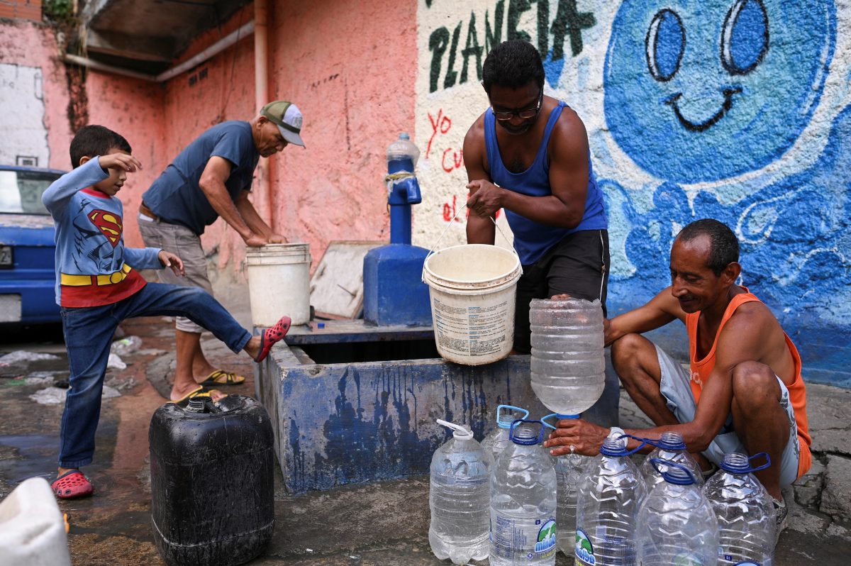 People extract water from an unknown source in the low-income neighborhood of Petare, in Caracas, Venezuela May 12, 2023. REUTERS/Gaby Oraa