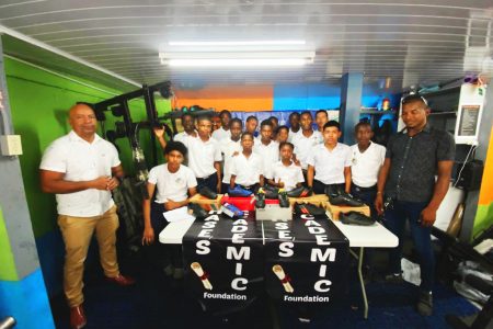 Exclusive Egg-Ball owner Randy Bourne (right) presents several pairs of football cleats to defending champion Chase Academy to aid in their preparation for the Digicel Schools Football Champion. Also in the photo are members of the team and school Principal Henry Chase (left)