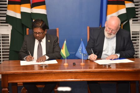 Finance Minister Dr Ashni Singh (left) and Executive Vice President of the European Commission Frans Timmermans signing the agreement at State House yesterday. 