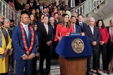 Assemblywoman Jennifer Rajkumar (at rostrum) and Mayor Eric Adams at yesterday’s press conference.