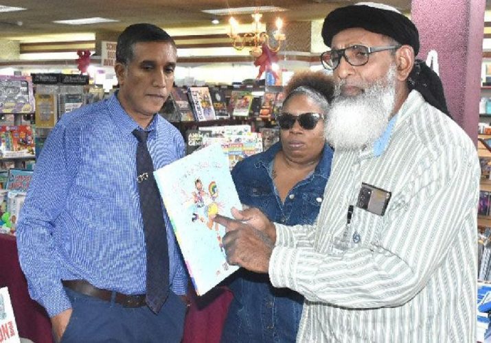 Umar Abdullah ,right founder leader of The First Wave Movement displays a children’s book titled I Am a Rainbow while speaking to reporters on Thursday about the content of the book on sale at RIK Services Ltd. bookstore on High Street, San Fernando . Looking on is Ruby Jemm and an offical of the bookstore. Abudullah is objecting to the sale of book at the bookstore. Photo:TREVOR WATSON