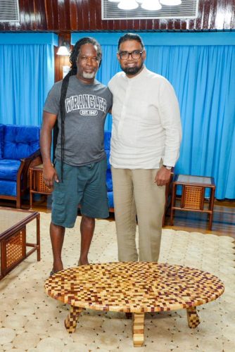 Troy Roberts (left) with President Irfaan Ali and the table (Office of the President photo)