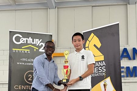 Century 21 representative Tyrell John (left) presenting the Open Divisional championship trophy to winner Alexander Zhang 