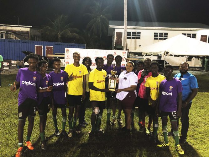 Buxton Secondary captain Omari Edwards collecting the East Coast Demerara zonal title from Petra Organization’s Nareeza Latif in the presence of teammates and members of the coaching staff
