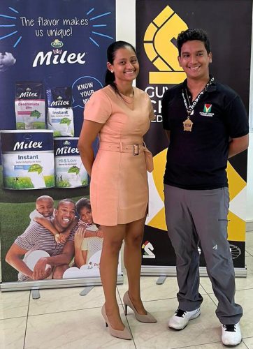 Ethan Lee posing with his medal alongside Alicia De Abreu, CEO of DeSinco Trading Ltd, after winning the National Junior Chess Qualifiers
