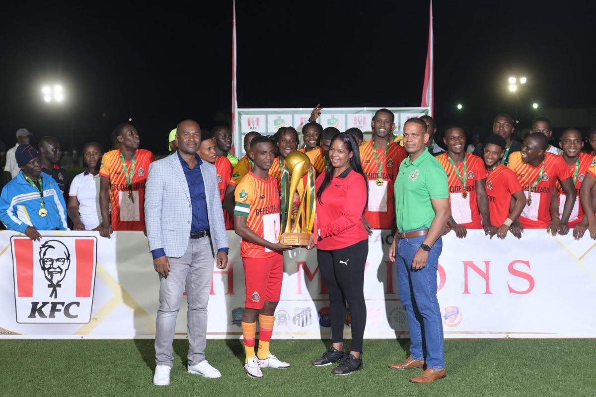 GDF captain Kenard Simon (2nd from left) receiving the championship trophy from KFC Marketing Manager Pamela Manasseh after winning the Elite League in the presence of Chief-of-Staff Brigadier Omar Khan (1st from right) and GFF President Wayne Forde