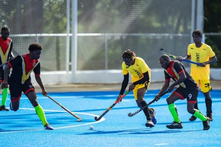 Andrew Stewart (right) of Guyana attempting to challenge in tandem with a teammate for possession of ball against Jamaica at the CAC Games
