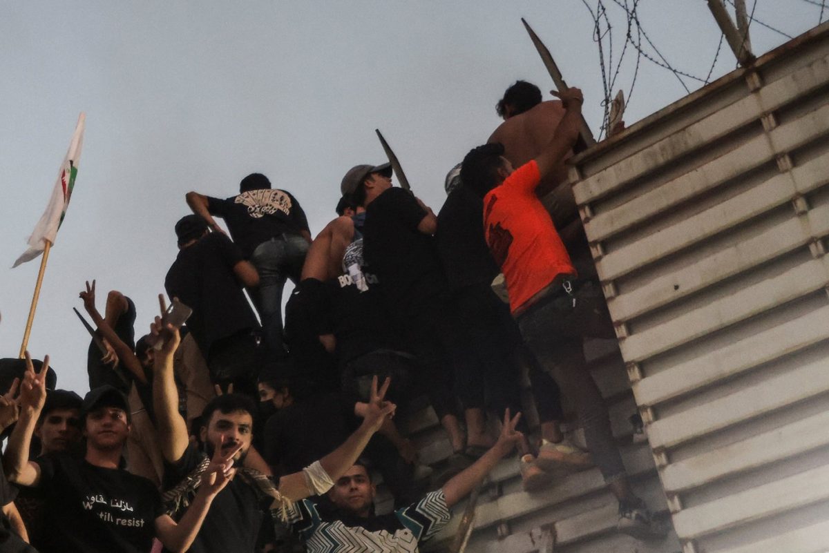 Protesters climb a fence as they gather near the Swedish embassy in Baghdad hours after the embassy was stormed and set on fire ahead of an expected Koran burning in Stockholm, in Baghdad, Iraq. Photo: Reuters