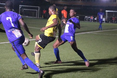 Western Tigers attacker Hubert Pedro trying to control the ball while being shadowed by two Anns Grove player
