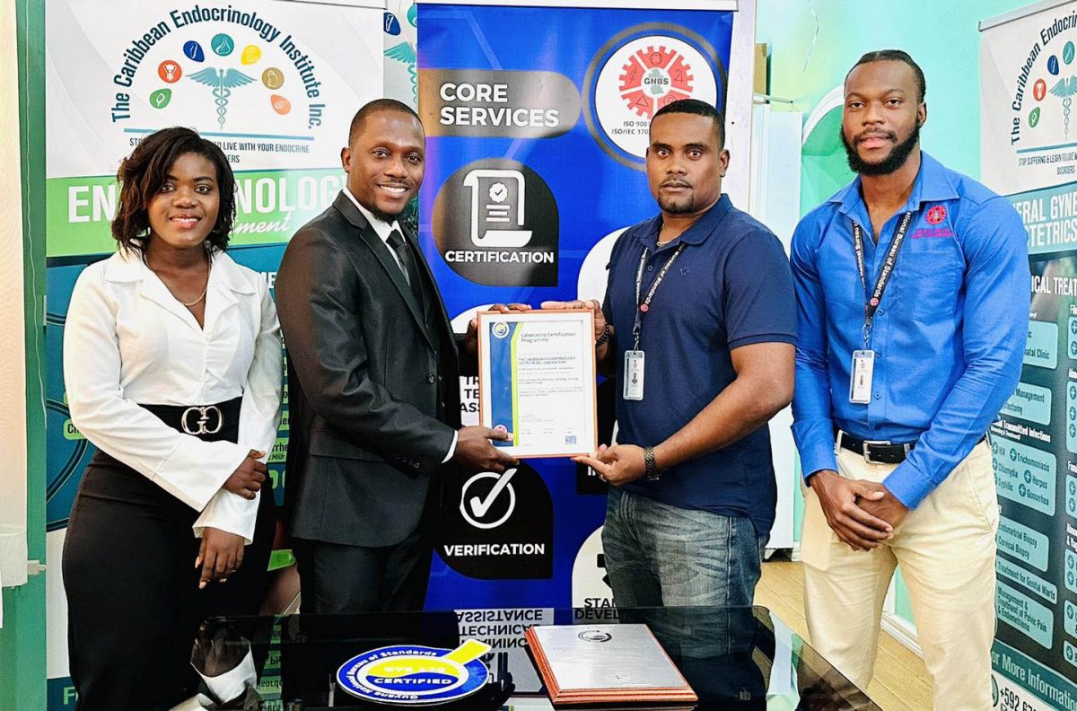 CEO & Head Consultant of the Caribbean Endocrinology Institute Inc, Dr. Caleb Mc Cloggan (second from left) receives the certificate from GNBS Head (Ag) of Certification Services, Keon Rankin. (GNBS photo)
