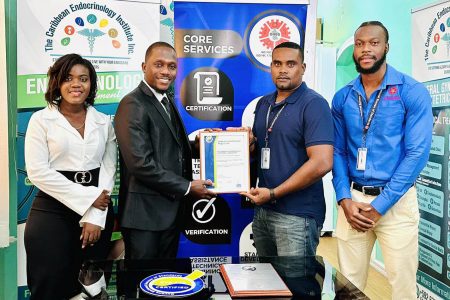 CEO & Head Consultant of the Caribbean Endocrinology Institute Inc, Dr. Caleb Mc Cloggan (second from left) receives the certificate from GNBS Head (Ag) of Certification Services, Keon Rankin. (GNBS photo)
