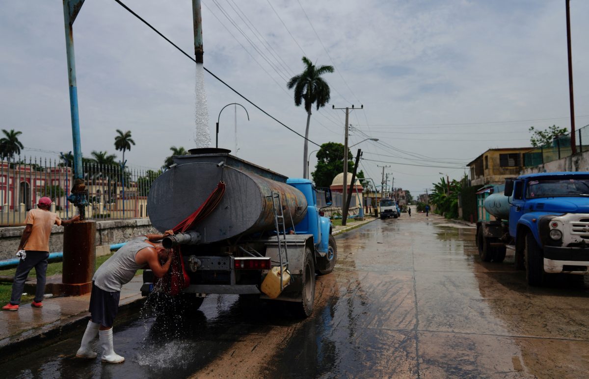 A driver refreshes himself as he fills up the tank of a water truck in Havana, Cuba, July 3, 2023. REUTERS/Alexandre Meneghini