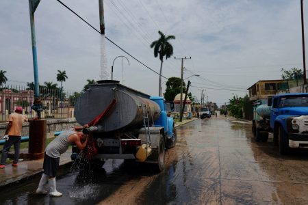 A driver refreshes himself as he fills up the tank of a water truck in Havana, Cuba, July 3, 2023. REUTERS/Alexandre Meneghini