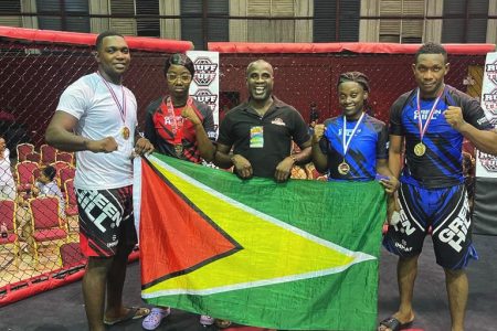 The Guyanese quartet [from left] of Carl Ramsay, Shenese Bobb, Anevia Frank and Ijaz Cave, alongside coach Troy Bobb (centre) displaying their spoils after winning four gold medals at the Ruff and Tuff Regional MMA League Invitational.