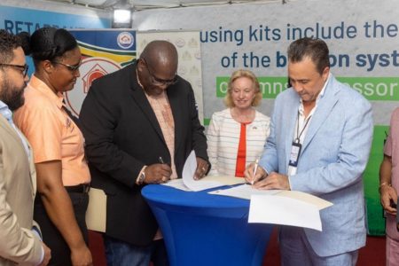 CHPA CEO Sherwyn Greaves and New Century International CEO, Alex De La Cruz (right)  signing the MoU. At centre is US Ambassador to Guyana Sarah-Ann Lynch.
