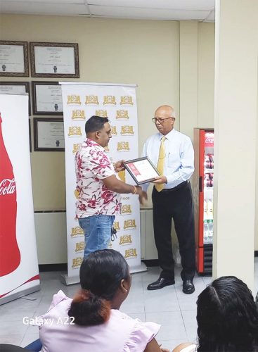 Sanjay Puran (left) receiving his certificate from Banks DIH Chairman, Clifford Reis.
