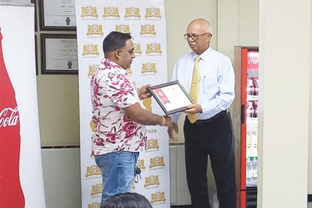 Sanjay Puran (left) receiving his certificate from Banks DIH Chairman, Clifford Reis.
