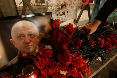 A man lays flowers at the makeshift memorial in honour of Yevgeny Prigozhin and Dmitry Utkin, who managed Wagner's operations and allegedly served in Russian military intelligence, in Moscow, on 24 August, 2023. Photo: AFP / Natalia Kolesnikova 