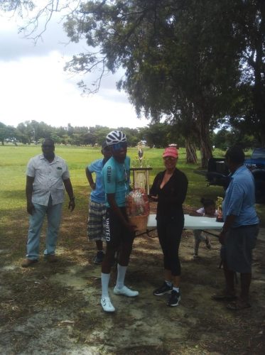 Briton John, winner of yesterday’s Ricks and Sari memorial race around the inner circuit of the National Park receives his trophy from Anna Perreira of the Ricks and Sari Company.