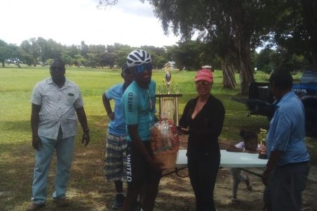 Briton John, winner of yesterday’s Ricks and Sari memorial race around the inner circuit of the National Park receives his trophy from Anna Perreira of the Ricks and Sari Company.