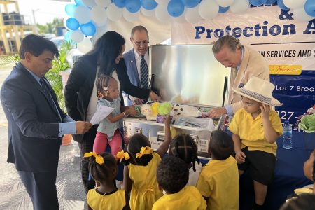 Minister of Human Services and Social Security, Dr. Vindhya Persaud; UNICEF Area Representative, Nicolas Pron; UNICEF Deputy Representative for Guyana & Suriname, Irfan Akhtar and High Commissioner of Canada to Guyana, Mark Berman along with students of the Lovable Friends and Kiskadee Daycare centres inspect an Early Childhood Development kit at the handover ceremony. (UNICEF Guyana photo)